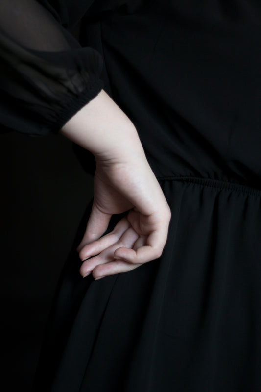 A hand rests on a black dress