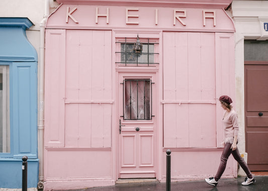 A woman walks past a pink storefront.